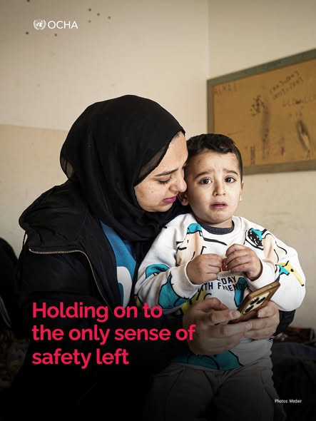 A mother holding her young child in a temporary shelter